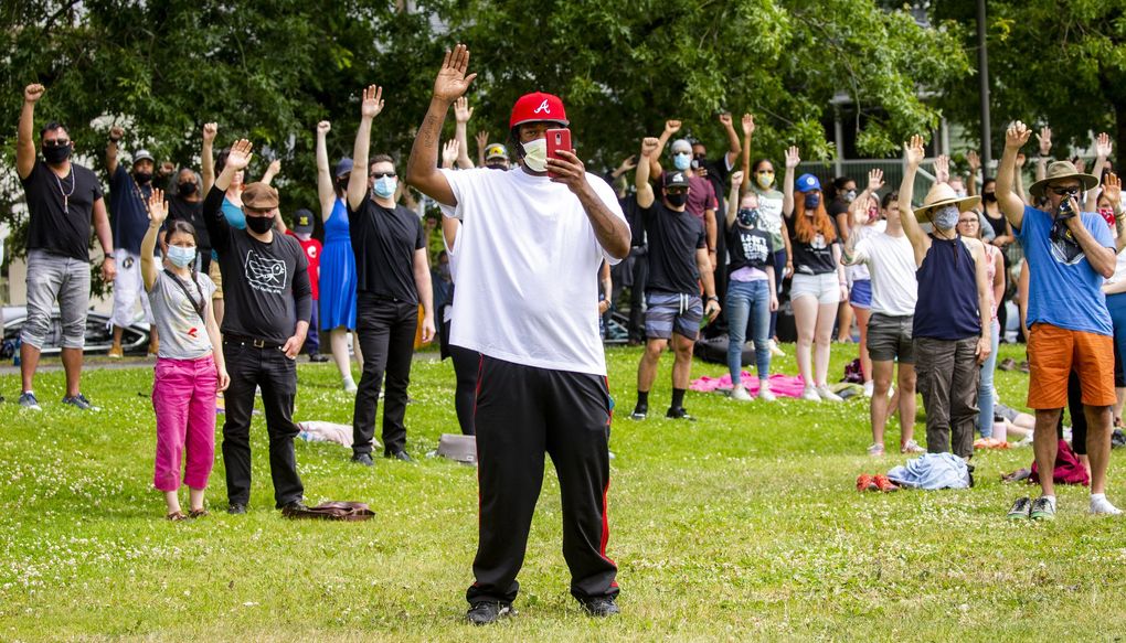 Community members stand to acknowledge the death of Jesse Sarey as his foster mom, Elaine Simons, speaks at a June rally in Seattle that gathered families affected by police violence, elected officials and community and business leaders. (Bettina Hansen / The Seattle Times)