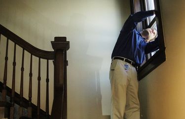 A home inspector checks a window in the stairwell of  an 107-year-old home in Denver .  Cyrus McCrimmon, The Denver Post, 2008.