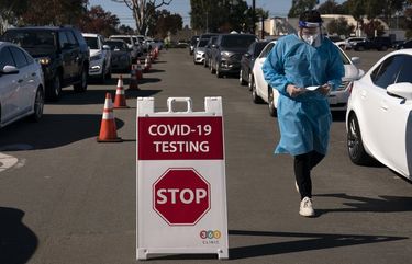 FILE – In this Nov. 16, 2020, file photo, student nurse Ryan Eachus collects forms as cars line up for COVID-19 testing at a testing site set up the OC Fairgrounds in Costa Mesa, Calif. Orange County will provide up to half a million mail-in test kits to residents before the end of the year in the hopes that more testing can help beat back the coronavirus. Orange County will offer the free test kits initially to residents of its two largest cities, Anaheim and Santa Ana. Health officials hope to make the kits available to all of the county’s 3 million residents by next month in what could be a massive boost in testing. unemployment rate stubbornly high. (AP Photo/Jae C. Hong, File) LA221 LA221
