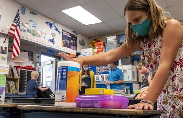 Parkway Elementary School fourth grader Joslyn Walkup places a canister of bleach wipes on her desk as she sets up her learning space on the first day of class on Wednesday, Aug. 26, 2020, in Clarkston, Wash.