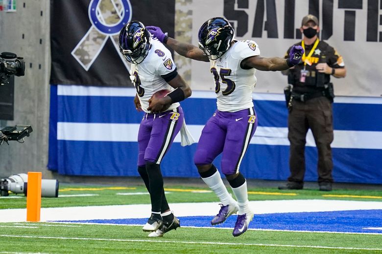 Baltimore Ravens' Lamar Jackson (8) hands off to Gus Edwards (35