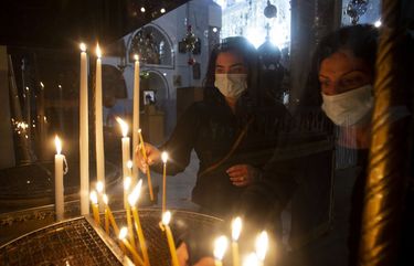 Christian worshippers light candles in the Church of the Nativity, traditionally believed to be the birthplace of Jesus Christ, in the West Bank city of Bethlehem, Monday, Nov. 23, 2020. Normally packed with tourists from around the world at this time of year, Bethlehem resembles a ghost town – with hotels, restaurants and souvenir shops shuttered by the pandemic. (AP Photo/Majdi Mohammed) DV557 DV557