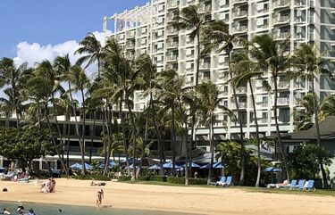 People are seen on the beach and in the water in front of the Kahala Hotel & Resort in Honolulu, Sunday, Nov. 15, 2020. Some locals in the tourism-dependent state have mixed feelings about the return of visitors during the pandemic after enjoying Hawaii beaches with dramatically fewer tourists since March. (AP Photo/Jennifer Sinco Kelleher) FX210 FX210