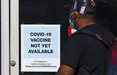 FILE – In this Dec. 2, 2020, file photo, a customer walks past a sign indicating that a COVID-19 vaccine is not yet available at Walgreens in Long Beach, Calif. (AP Photo/Ashley Landis, File) NYAG201 NYAG201