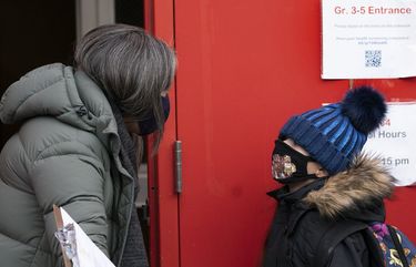 A school administrator, left, asks a student if his parents have completed a form granting permission for random COVID-19 testing as he arrives at P.S. 134 Henrietta Szold Elementary School, Monday, Dec. 7, 2020, in New York. Public schools reopened for in-school learning Monday after being closed since mid-November. (AP Photo/Mark Lennihan) NYML102 NYML102