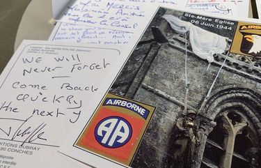 In this Tuesday, Dec. 15, 2020 photo, A handwritten post card from a resident of Sainte-Mere-Eglise, France thanks U.S. paratroopers for liberating their village from Nazi occupation, seen at Fort Bragg, N.C. The town sent 500 notes to Fort Bragg, North Carolina which were read by soldiers. 12,000 82nd paratroopers fought to liberate Normandy on June 6th, 1944. 1,400 were lost their lives in the invasion. (AP Photo/Sarah Blake Morgan) NCSM201 NCSM201
