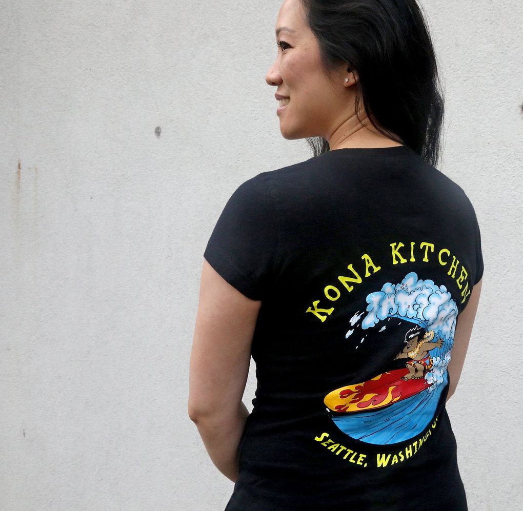 Angie Okumoto wears a Kona Kitchen tee shirt. They’re for sale at the restaurant. (Greg Gilbert / The Seattle Times)
