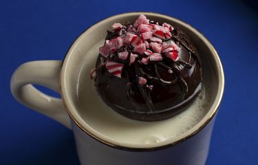 A hot chocolate bomb in a mug of hot milk, in New York, Dec. 7, 2020. A few ingredients go a long way when it comes to hot chocolate bombs, a cozy treat that has quickly gained popularity on social media. Styled by Liz Clayman. (Liz Clayman/The New York Times)