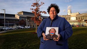 Laura Dilts, of Barre, Mass., holds a photograph of her 16-year-old son outside the Worcester Recovery Center, where he is a resident patient receiving assistance for his mental health, Monday, Nov. 23, 2020, in Worcester, Mass. The coronavirus pandemic has led to rising emergency room visits and longer waits for U.S. children and teens facing mental health issues. (AP Photo/Charles Krupa)