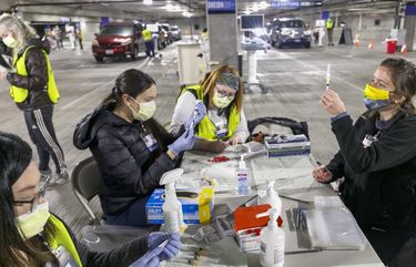 Medical professionals from Oregon Health & Science University load syringes with the Moderna COVID-19 vaccine at a drive-thru vaccination clinic in Portland, Ore., Sunday, Jan. 10, 2021. The clinic is a partnership between the Service Employees International Union and Oregon Health & Science University, aiming to vaccinate Oregon’s 32,000 home health care workers and their patients. (Kristyna Wentz-Graff/Pool Photo via AP) OROPB706 OROPB706