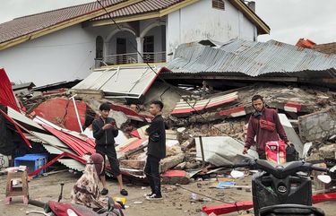 Residents stand near a building flattened by an earthquake in Mamuju, West Sulawesi, Indonesia, Friday, Jan. 15, 2021. A strong, shallow earthquake shook Indonesia’s Sulawesi island just after midnight Friday, toppling homes and buildings, triggering landslides and killing a number of people. (AP Photo/Rehan) XJAK117 XJAK117