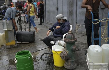 Residents tap into a fire hydrant to fill their containers with water in the San Juan neighborhood of Caracas, Venezuela, Tuesday, Jan. 19, 2021, amid the new coronavirus pandemic. Venezuela’s economic crisis has sent millions fleeing and those left behind lacking basic goods, including gasoline, in a country with one of the world’s largest proven oil reserves. (AP Photo/Matias Delacroix) XMD105 XMD105