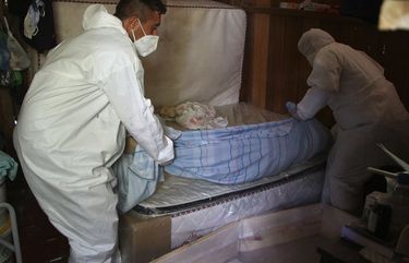 Public funeral service workers remove the body of Amelia Dias Nascimento, 94, who died from complications related to COVID-19 in her home, in Manaus, Amazonas state, Friday, Jan. 22, 2021. The number of people who die in their homes amid the new coronavirus pandemic is growing due to the lack of availability in hospitals and the shortage of oxygen. (AP Photo/Edmar Barros) XAP107 XAP107