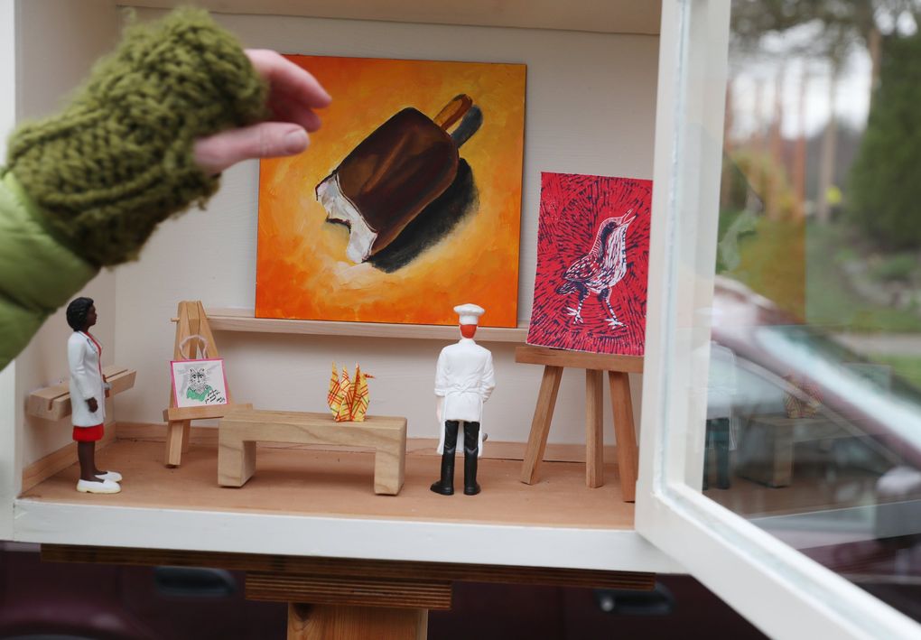 Stacy Milrany sets up a painting, at center, that was left anonymously for her Little Free Art Gallery, where people can take or leave tiny artworks. (Ken Lambert / The Seattle Times)
