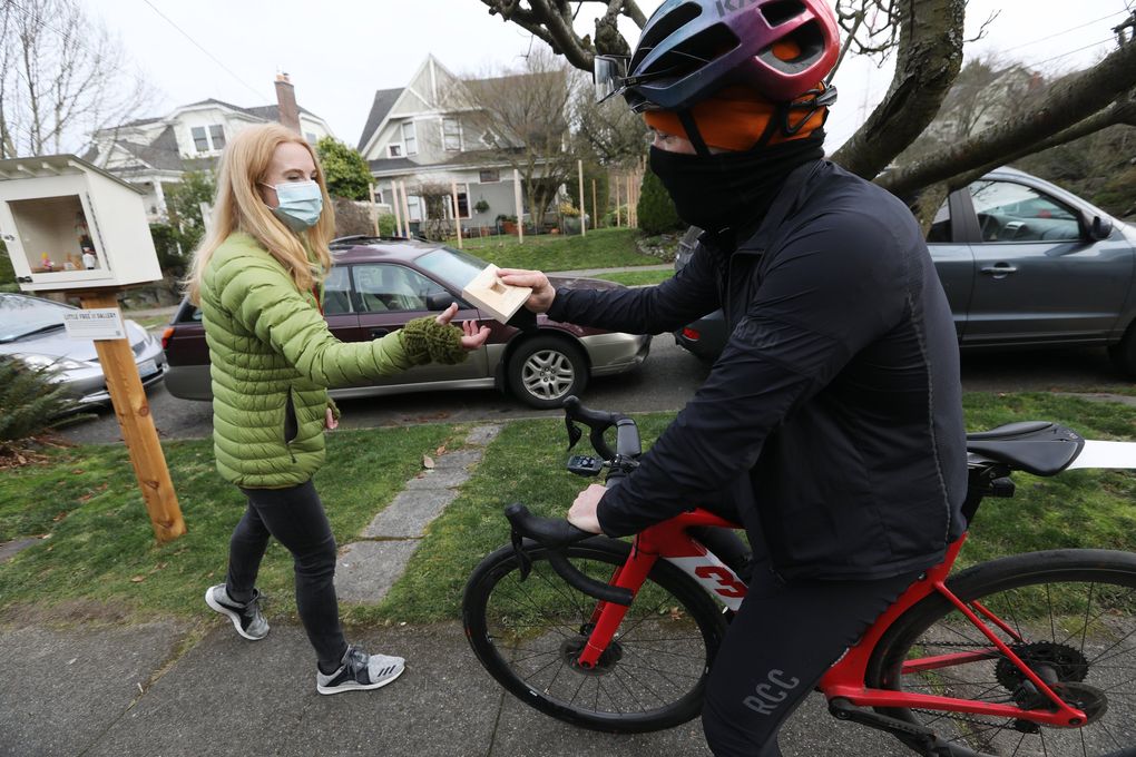 Artist Harold Hollingsworth of Seattle, right, biked from Ballard to Queen Anne to give Stacy Milrany, left, a small artwork of his for Milrany’s Little Free Art Gallery. (Ken Lambert / The Seattle Times)