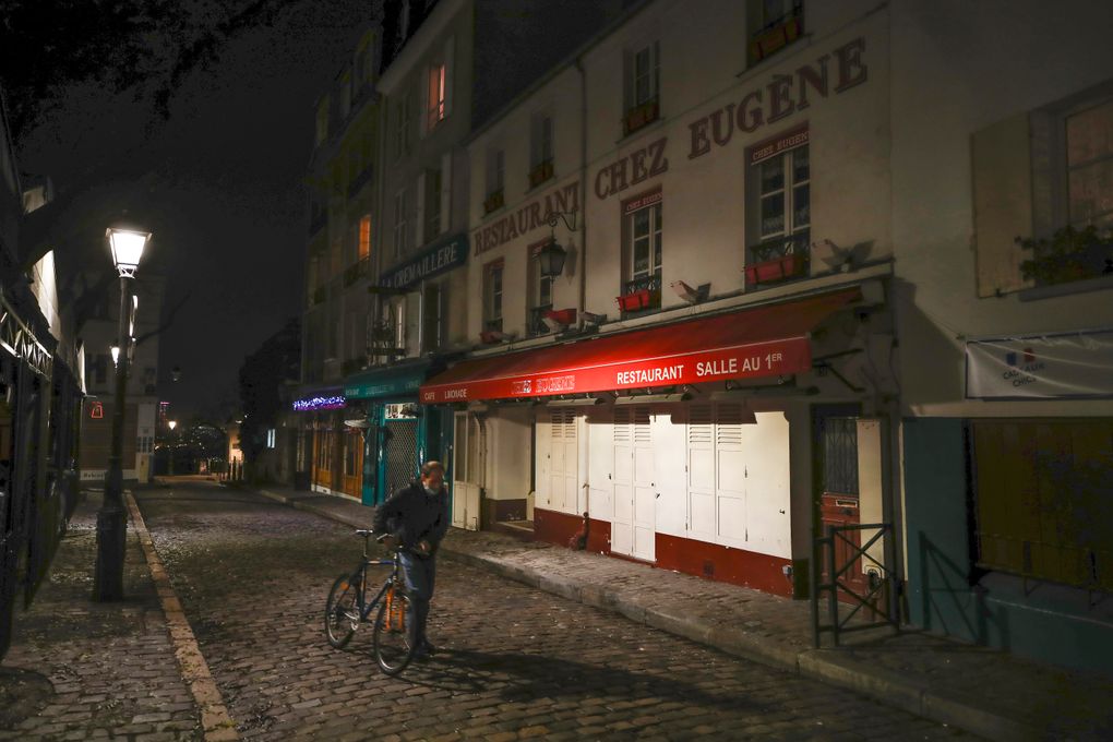 FILE – In this Dec. 15, 2020 file photo, a man pushes his bicycle along a row of closed restaurants in Montmartre, during the new imposed curfew in Paris. Trying to fend off the need for a third nationwide lockdown that would further dent Europe’s second-largest economy and put more jobs in danger, France is instead opting for creeping curfews. (AP Photo/Michel Euler, File)