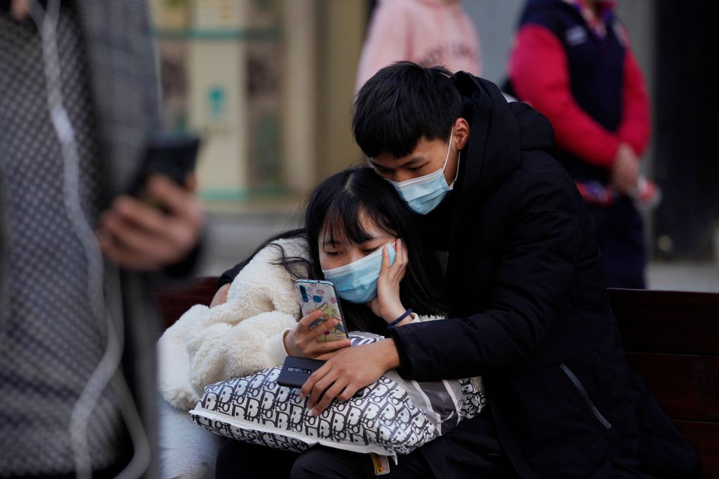 A man and woman wearing masks to help protect themselves from the coronavirus share a smartphone on the street in Wuhan in central China’s Hubei province on Thursday, Jan. 14, 2021. A global team of researchers for the World Health Organization arrived Thursday in the Chinese city where the coronavirus pandemic was first detected to conduct a politically sensitive investigation into its origins amid uncertainty about whether Beijing might try to prevent embarrassing discoveries. (Ng Han Guan / The Associated Press)