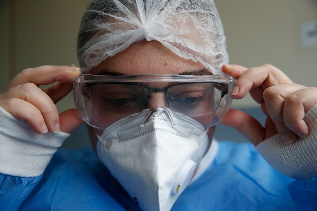Cleaning worker Anthoula Dimitra Pagouni, 30, wears protective gear before entering an ICU at the Sotiria Thoracic Diseases Hospital in Athens, Monday, Jan. 18, 2021. The cleaners of coronavirus intensive care units run a daily gauntlet of infection risks to ensure that ICUs run smoothly, and they are critical to preventing the spread of disease in hospitals. But their status as unskilled laborers in a behind-the-scenes role has left them out of the public eye. (AP Photo/Thanassis Stavrakis)