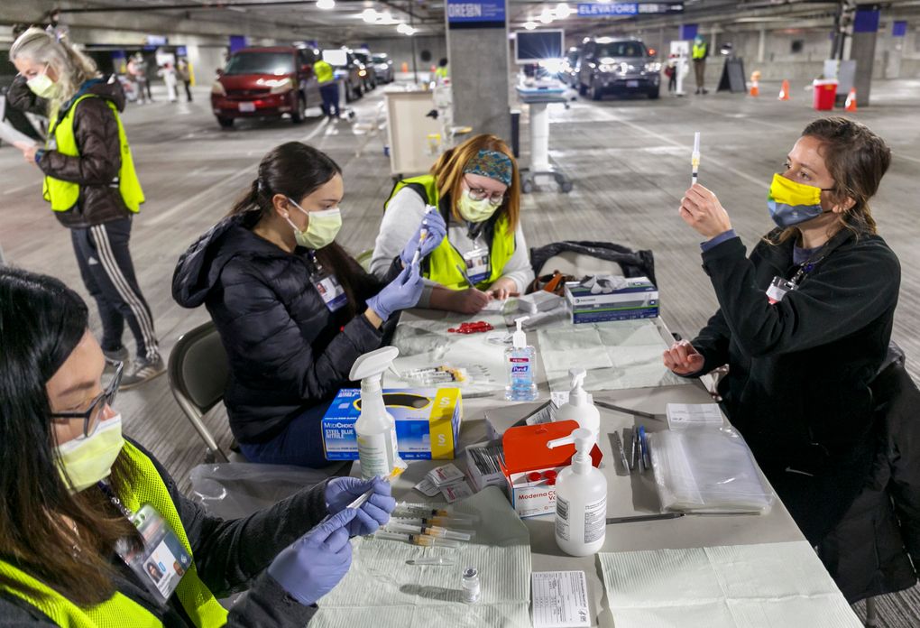 FILE – In this Sunday, Jan. 10, 2021, file photo, Medical professionals from Oregon Health & Science University load syringes with the Moderna COVID-19 vaccine at a drive-thru vaccination clinic in Portland, Ore. The U.S. is entering the second month of the largest vaccination effort in history with a massive expansion of the campaign, opening up football stadiums, major league ballparks, fairgrounds and convention centers to inoculate a larger and more diverse pool of people. (Kristyna Wentz-Graff / The Associated Press)