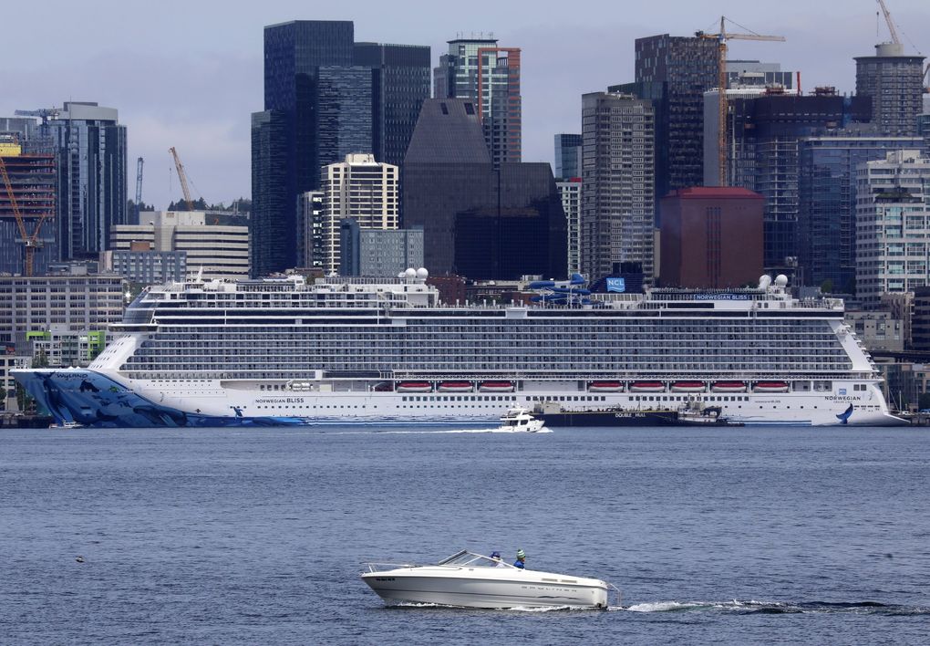 A cruise ship dwarfs a pleasure boat, as well as some of the Seattle skyline, in this view from Alki Beach. Cruise ships normally bound for Alaska via Canada will have to wait longer to sail. (Ken Lambert / The Seattle Times)