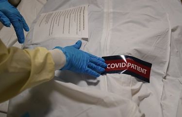 FILE – In this Jan. 9, 2021, file photo, a hospital worker places a “COVID Patient” sticker on a body bag holding a deceased patient at Providence Holy Cross Medical Center in the Mission Hills section of Los Angeles. Coronavirus hospitalizations are falling across the United States, but deaths have remained stubbornly high. (AP Photo/Jae C. Hong, File) NYAG401 NYAG401