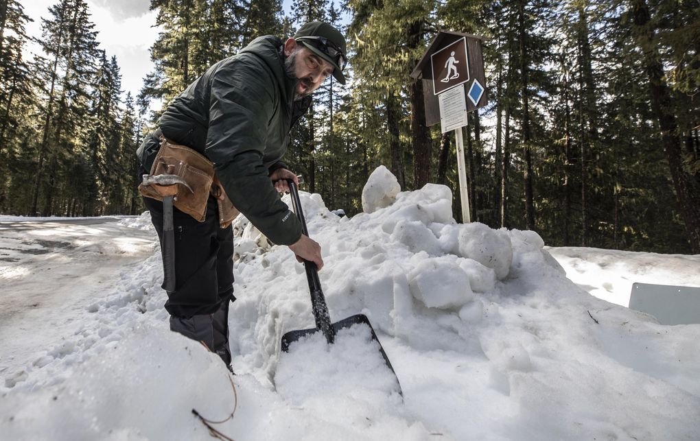 Jason Goldstein of Washington State Parks plants digs stairs into the berm off Salmon La Sac Road near Cle Elm River Campground, the site of a new temporary Sno-Park. The site was built in response to overpopulation at existing snow play areas and heavy demand for more access points accessible from Greater Seattle. (Steve Ringman / The Seattle Times)