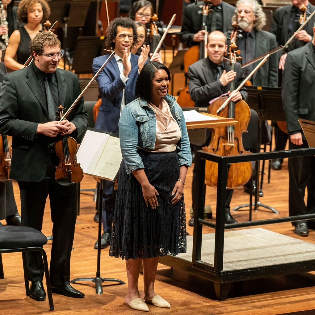Composer Hannah Kendall (front center) with conductor Jonathon Heyward (behind her) during Seattle Symphony’s U.S. premiere of Kendall’s “The Spark Catchers” in 2019. (James Holt / Seattle Symphony)