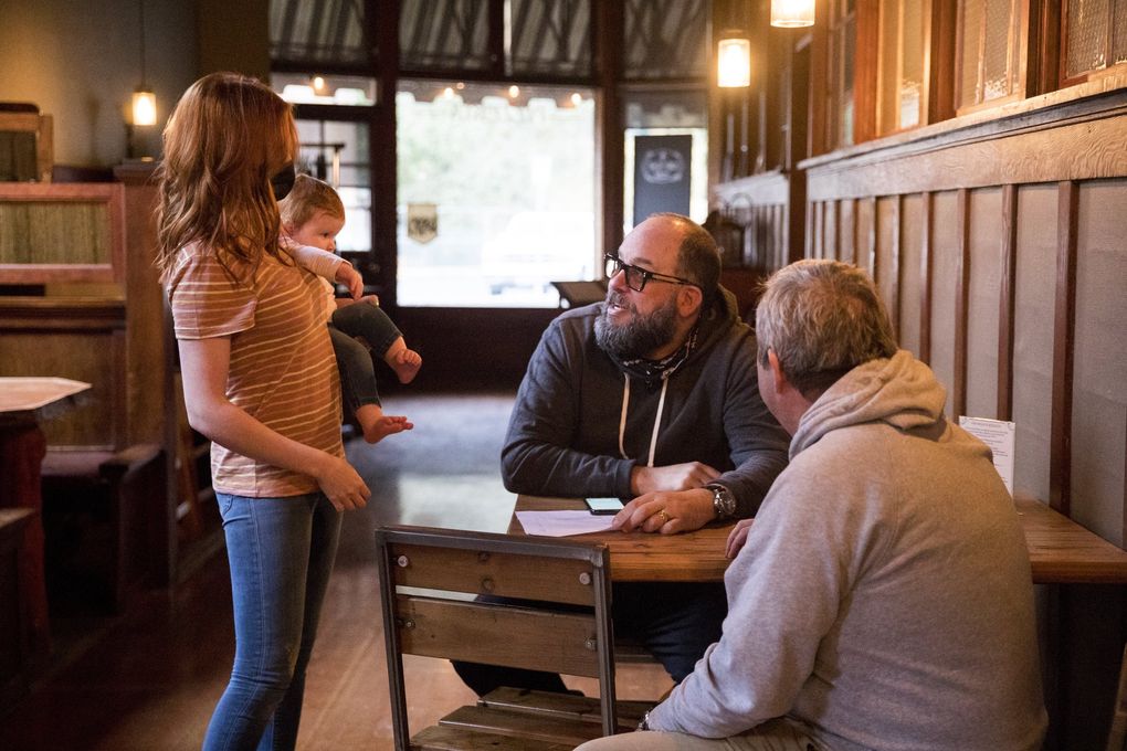 Ashley Galbraith and her daughter, Cleo, take orders from John Xitco, center, and Scott Carroll, right, at The Carlson Block earlier this month. (Amanda Snyder / The Seattle Times)