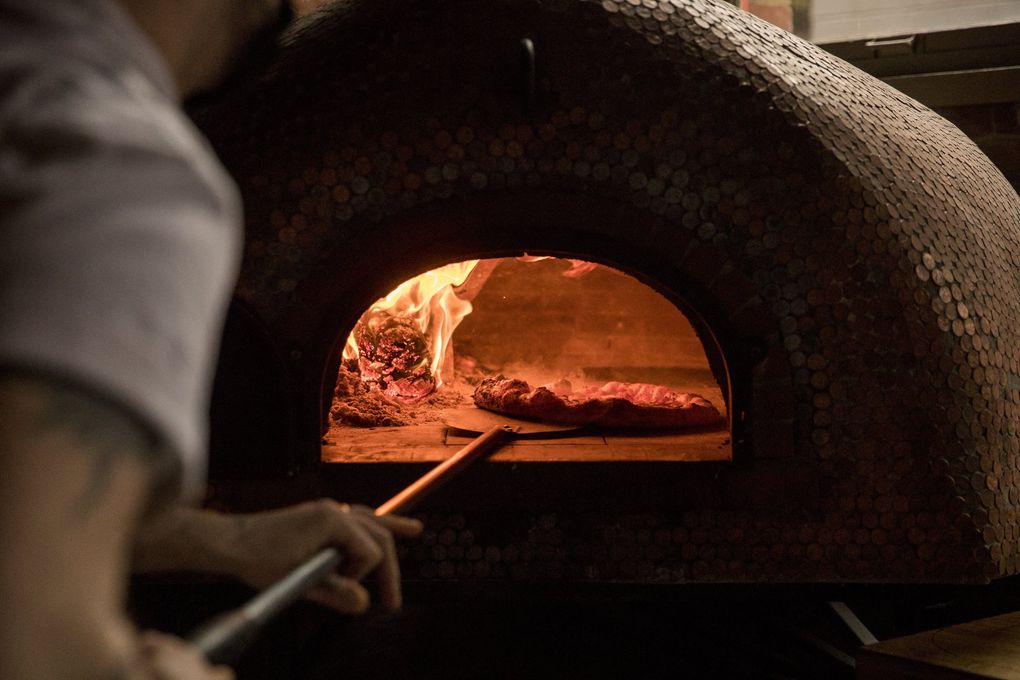 Ian Galbraith puts a pizza into the oven at The Carlson Block in Wilkeson. (Amanda Snyder / The Seattle Times)