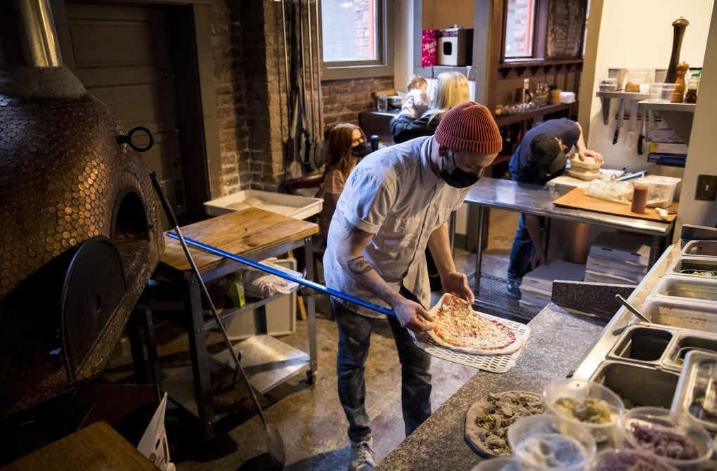 Ian Galbraith prepares a pizza to put in the wood-fired oven at The Carlson Block, which he owns with his wife, Ashley. The Carlson Block resides in a 110-year-old former hotel in Wilkeson. (Amanda Snyder / The Seattle Times)