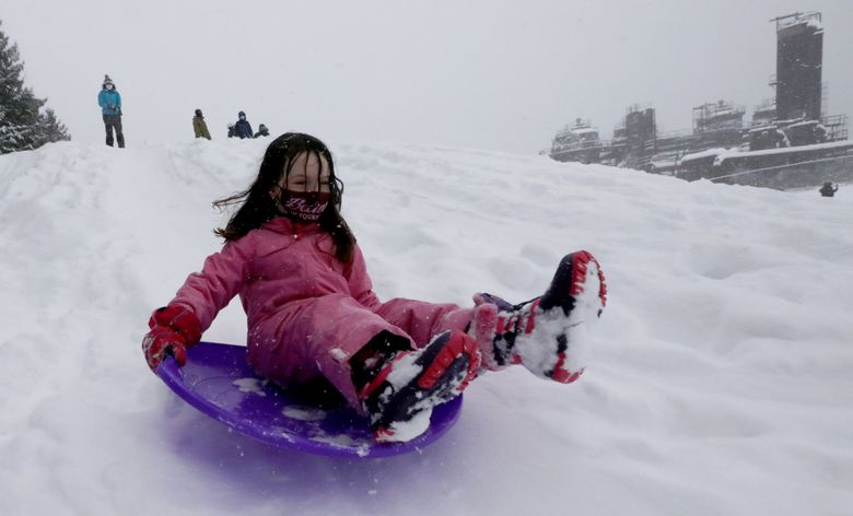 Adina Cook, 7, slides down a hill at Gas Works Park.  The family decided not to go to Snoqualmie Pass to ski, but instead stay in the city. (Alan Berner / The Seattle Times)