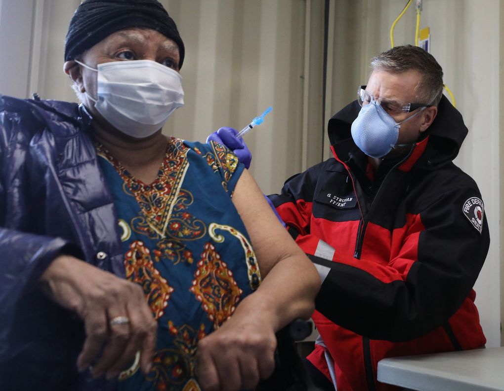 Rosetta DeCuir receives the first dose of the COVID-19 vaccine from Seattle firefighter Garth Stroyan on Thursday at the 2801 SW Thistle St. site. (Alan Berner / The Seattle Times)