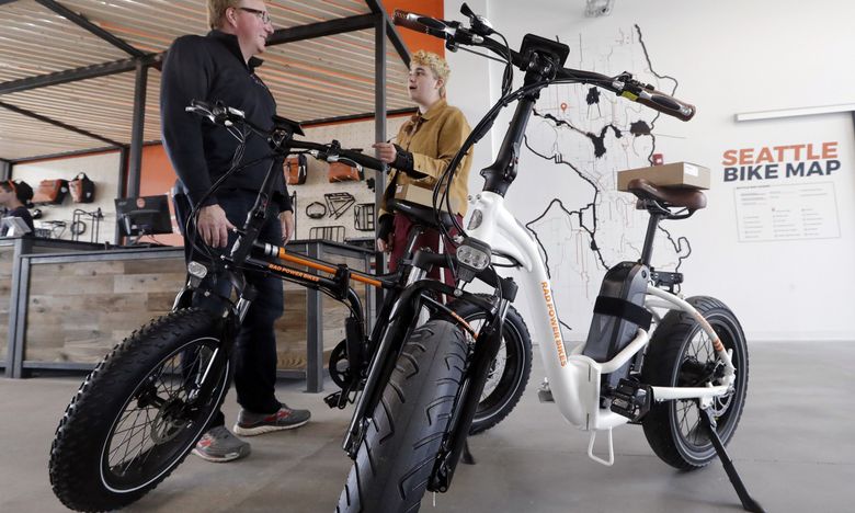 In this photo taken in May, 2019, customer Torre Treece, left, talks with Rad Power Bikes sales associate Becs Richards about the two electric bikes he bought at the shop in Seattle.  (AP Photo/Elaine Thompson)  (Elaine Thompson / AP)
