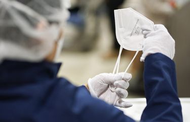 Workers inspect the quality of N95 masks on the production line at United States Mask in Fort Worth, Texas, Feb. 5, 2021. (Cooper Neill/The New York Times)