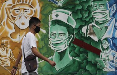 A man wearing a protective mask to prevent the spread of the coronavirus walks beside a mural of health workers outside the Mission Hospital in Pasig, Philippines, Monday, Feb. 22, 2021. Delays have hounded the delivery of COVID-19 to the Philippines, with officials saying the scheduled arrival on Tuesday of 600,000 doses of donated vaccine from Sinovac Biotech Ltd. may be delayed because the China-based firm still lacks an authorization from Manila’s Food and Drug Administration for the emergency use of it’s vaccine. (AP Photo/Aaron Favila) XAF102 XAF102