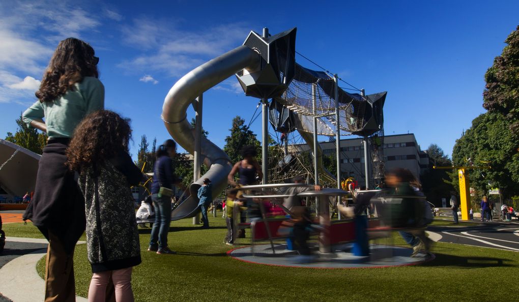 In pre-pandemic times, a woman and child watch other kids playing at the “Artists at Play” playground at Seattle Center Wednesday, September 16, 2015. How will the children who went through their formative years in the COVID-19 era adapt to social interaction in the post-pandemic era? It’s hard to say. (Ellen Banner/The Seattle Times)