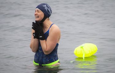 Tamra Sherwood reacts to the bracing cold water during an open-water swim at Alki Beach in West Seattle on a snowy Sunday February 14, 2021. 216352