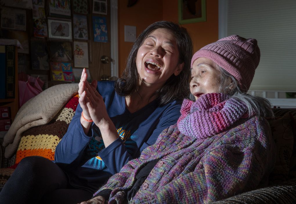 Trang Tu sings with her mother, Anna Nguyet Dang, in the Seattle home they share on Feb. 1. Trang helped form a collective that encouraged the state to add people 55 and over in home care to be prioritized in Phase 1B1. She has been caring for her mother with dementia for five years. Now that the program has been rolled out, she and others in the refugee and immigrant community say that BIPOC elders (Black, Indigenous and people of color) are facing many challenges in accessing vaccines. (Ellen M. Banner / The Seattle Times)