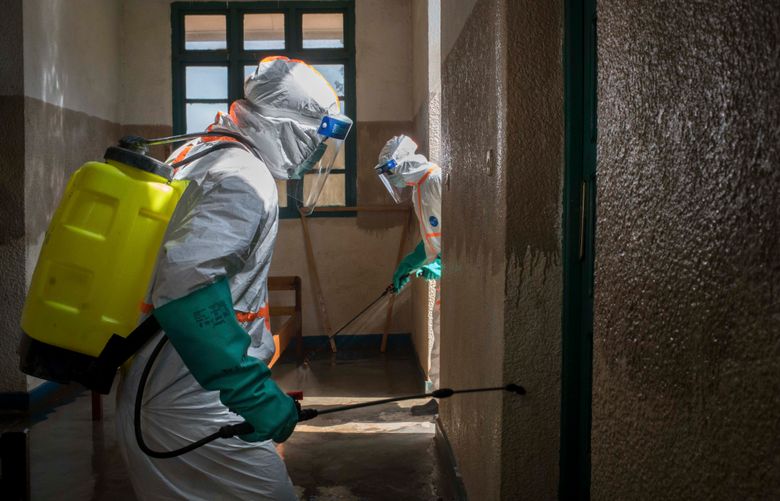 FILE — Sanitation workers decontaminate a hospital during an Ebola outbreak in Butembo, Democratic Republic of Congo, Dec. 7, 2018. A woman who was in contact with at least 70 people has died of Ebola in a violence-plagued region of the Democratic Republic of Congo. It could signal the start of the 12th outbreak of the virus in the country. (Diana Zeyneb Alhindawi/The New York Times)