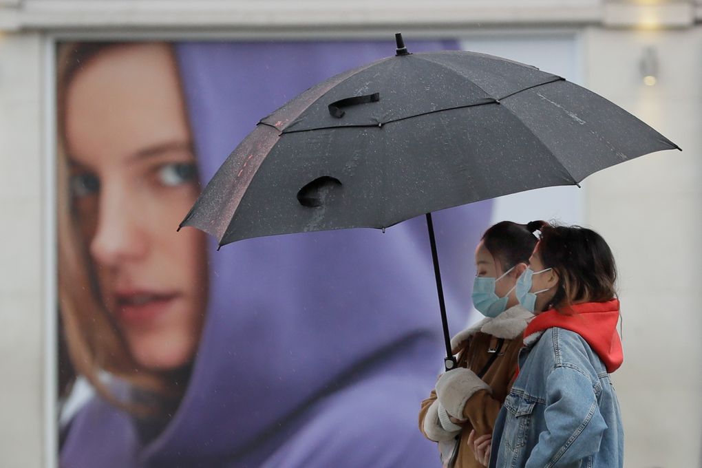 People wear masks to protect against coronavirus as they pass a shop in London, Wednesday, Feb. 3, 2021. Britain’s Health Secretary Matt Hancock said Wednesday a new study suggesting that a single dose of the AstraZeneca vaccine may reduce transmission of COVID-19 categorically supports the government’s strategy of taking more time between injections. (AP Photo/Kirsty Wigglesworth)