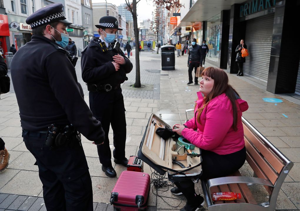 Police officers speak to a busker as they patrol to enforce lockdown measures in the town centre of Ilford in London, Friday, Jan. 29, 2021. In parts of east London, the pandemic is hitting much harder than most places in the U.K. The borough of Redbridge had the nation’s second worst infection rate in January, with an estimated 1 in 15 residents thought to be infected. (AP Photo/Frank Augstein)