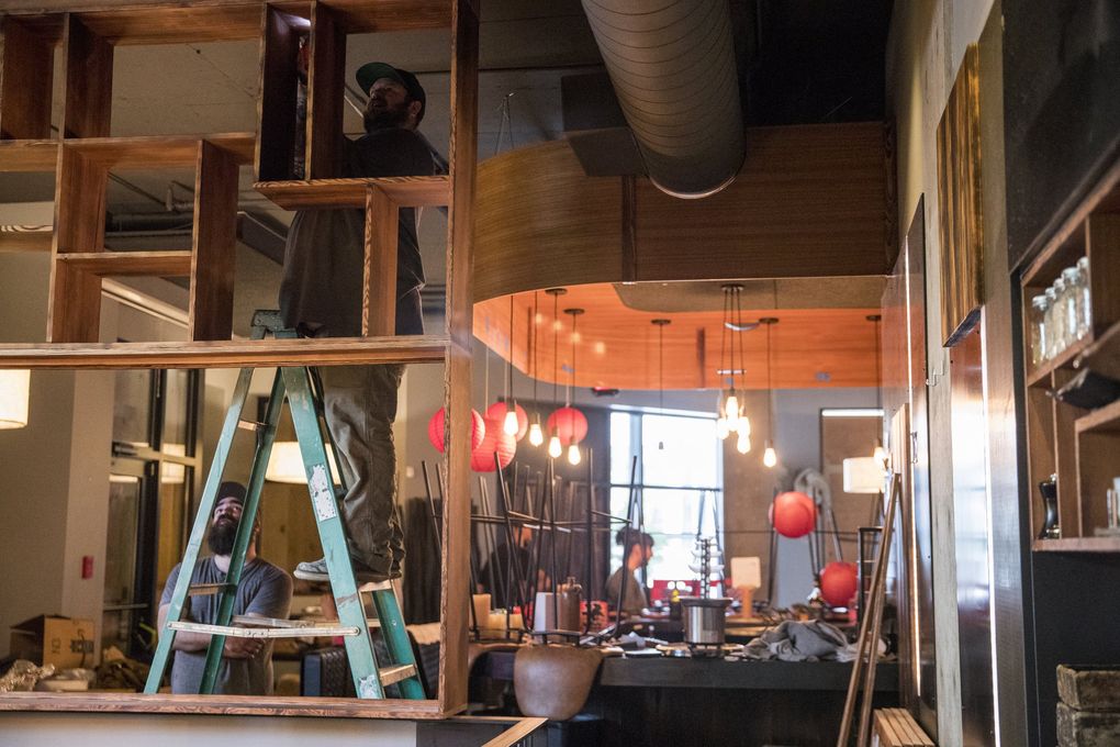 Bodhi Builders owner Chris Kinkae, above, and employee Calvin Ocasia, left below, take down wooden framework as Adana is cleared out on Thursday, May 21, 2020. A friend of chef Shota Nakajima, Kinkae built the special framing for the space. (Amanda Snyder / The Seattle Times)