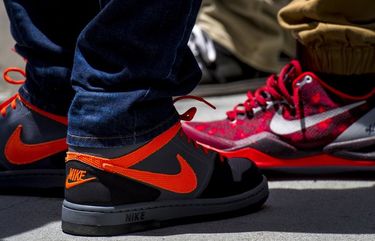 Pedestrians wearing Nike Inc. shoes stand on a sidewalk in front of a store in San Francisco, California, U.S., on Tuesday, June 24, 2014. Nike Inc. is scheduled to release earnings figures after the close of U.S. financial markets on June 26. Photographer: David Paul Morris/Bloomberg 499592677