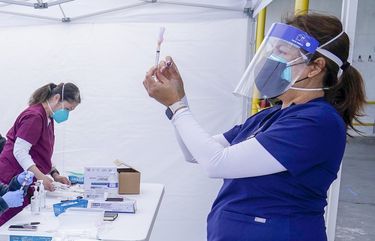 FILE – In this March 3, 2021, file photo, public health nurse Dyah Moore, right, and other health care workers prepare Moderna COVID-19 vaccines for farmworkers at a County of Santa Clara mobile vaccination clinic at Monterey Mushrooms, an agricultural employer under the United Farm Workers union contract, amid the coronavirus pandemic in Morgan Hill, Calif. In some California counties, vaccination drives are targeting farmworkers. (AP Photo/Jeff Chiu, File) NYAG402