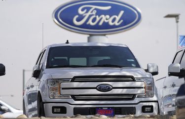 FILE – In this Sunday, Oct. 11, 2020, file photo, a row of 2020 sports-utility vehicles pickup trucks sits at a Ford dealership, in Denver. Ford Motor Co. lost $1.28 billion last year as it dealt with the coronavirus pandemic that forced it to shut down U.S. factories for about two months. But the automaker said Thursday, Feb. 4, 2021, it is generating strong cash flow and will go all-in on electric vehicles. (AP Photo/David Zalubowski, File)