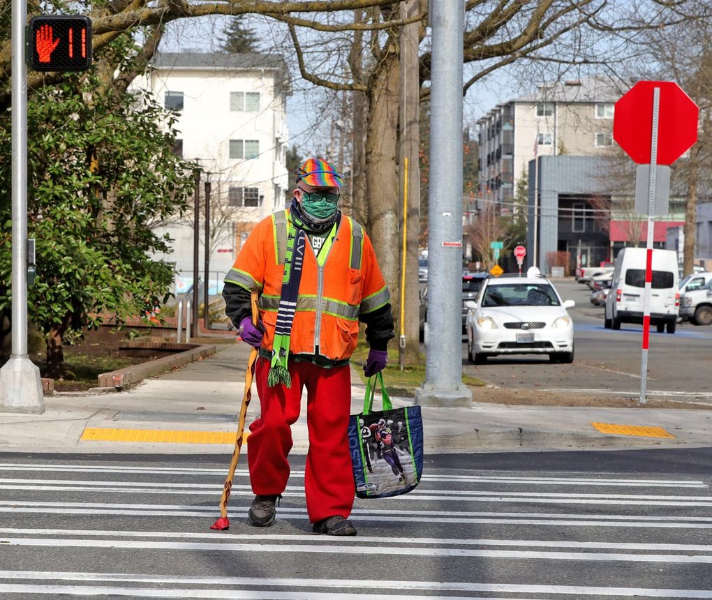 Lars Sveum-Hanson, 74, crosses the new crosswalk at Northeast 125th and 29th Avenue Northeast. He says he sometimes feels unsafe walking in his neighborhood despite wearing an orange vest and a bright-colored hat. (Greg Gilbert / The Seattle Times)