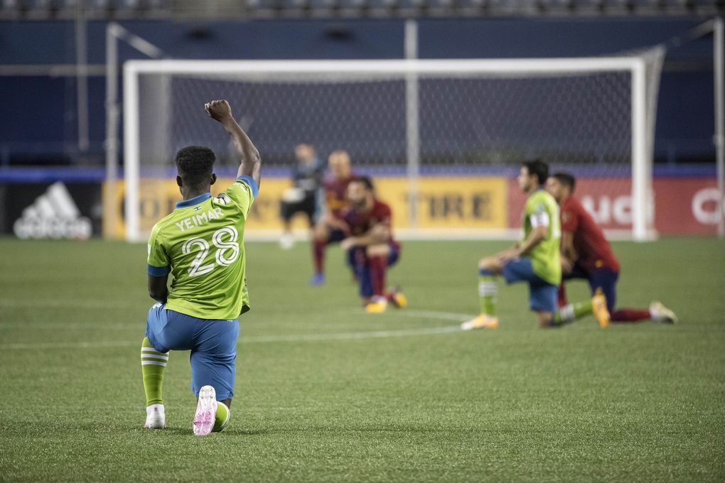 Players take a knee before the start of Wednesday’s match. -Yeimar Gomez being one of several players to raise his fist. Real Salt Lake played the Seattle Sounders FC in MLS action Wednesday, October 7, 2020 at CenturyLink Field in Seattle, WA. (Dean Rutz / The Seattle Times)