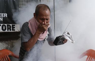 A resident holds his nose and portable radio as he tries to avoid the disinfectants used on their village as a precaution against the spread of COVID-19 in Manila, Philippines on Monday, March 15, 2021. The Department of Health has been reporting a surge in infections for more than a week, adding to concerns over a sluggish start of a vaccination campaign that has faced supply problems and public reluctance. (AP Photo/Aaron Favila) XAF104 XAF104