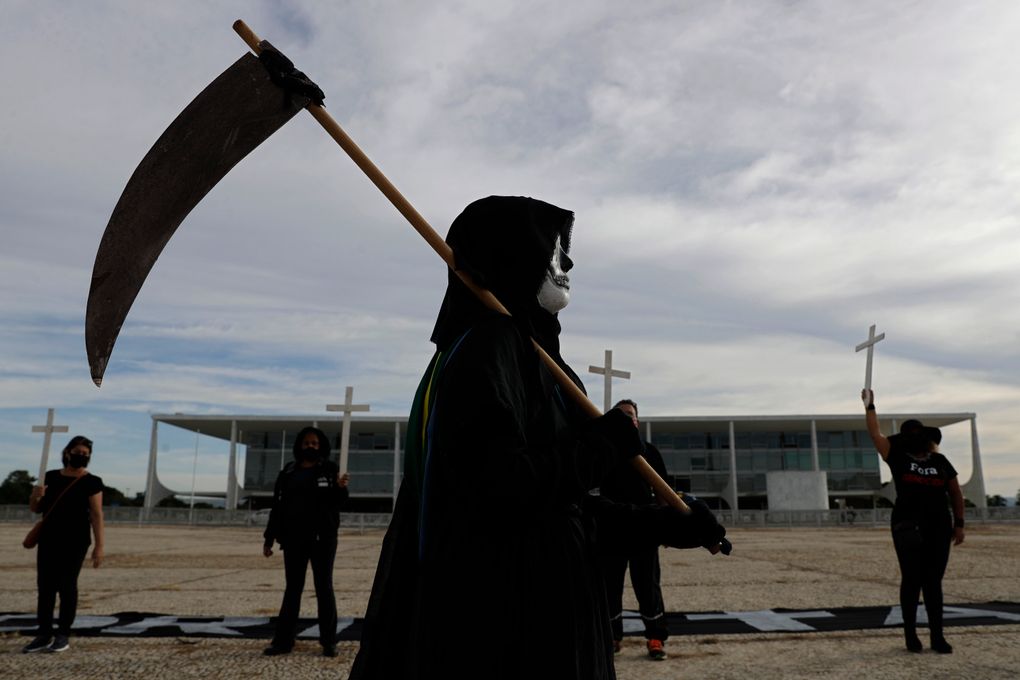 A demonstrator dressed as death performs outside Planalto presidential palace to protest the president’s handling of the COVID-19 pandemic in Brasilia, Brazil, Friday, March 26, 2021. Brazil surpassed 300,000 deaths from the virus this week. (AP Photo/Eraldo Peres)