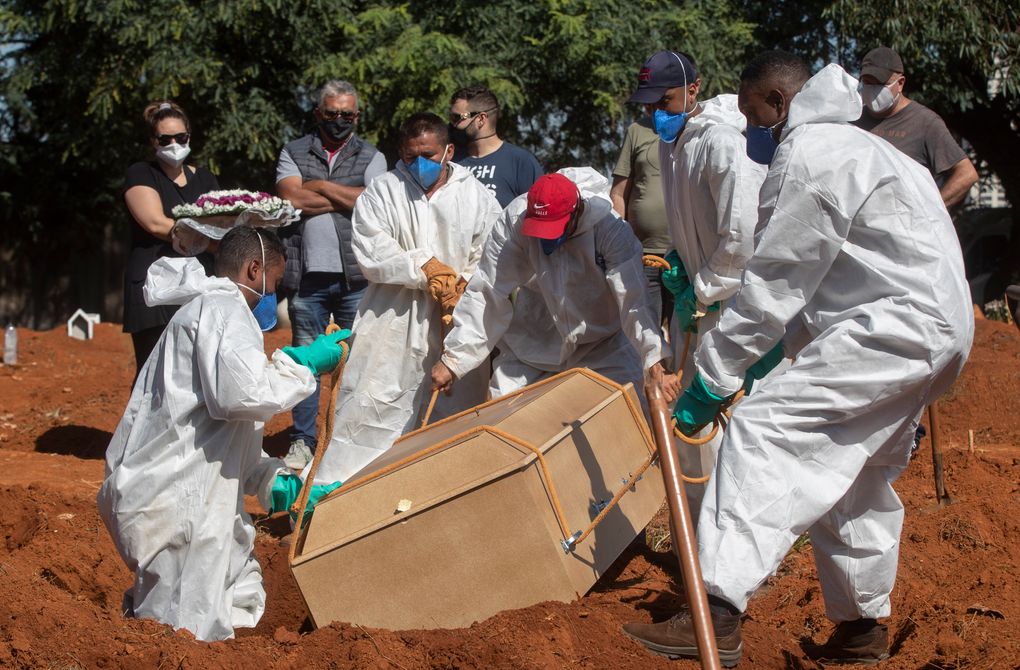 Cemetery workers in full protective gear lower a coffin that contain the remains of a person who died from complications related to COVID-19 at the Vila Formosa cemetery in São Paulo, Brazil, Wednesday, March 24, 2021. Daily deaths in Brazil hit a record 3,251 Tuesday. (André Penner / AP)